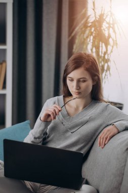 Evde dizüstü bilgisayarla çalışan genç bir kız.