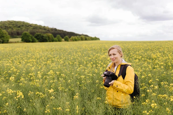 Glimlachende vrouw op het veld met digitale camera — Stockfoto