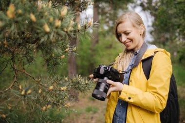 Ormanda çekilen fotoğrafları inceleyen mutlu kadın.