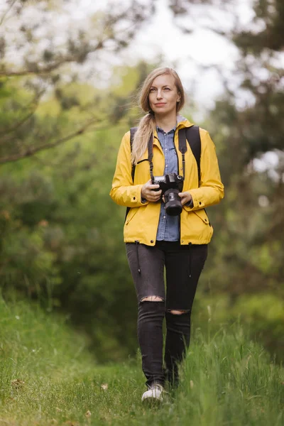 Vrouwelijke fotograaf loopt door groen bos — Stockfoto