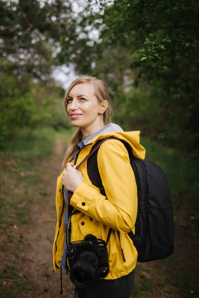 Charmante vrouw in het bos met rugzak en camera — Stockfoto