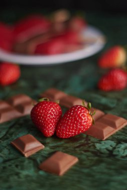 Yeşil arka planda çikolata parçalı taze çilekler ve dokular.