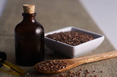 Beyaz arkaplanlı keten tohumu yağı ve beyaz bardakta keten tohumu.