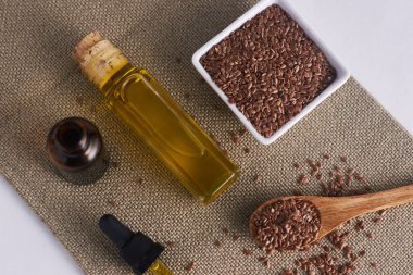 Beyaz arkaplanlı keten tohumu yağı ve beyaz bardakta keten tohumu.