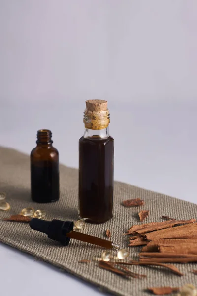 cinnamon oil in glass bottle and cinnamon in white cup and dropper with cinnamon oil