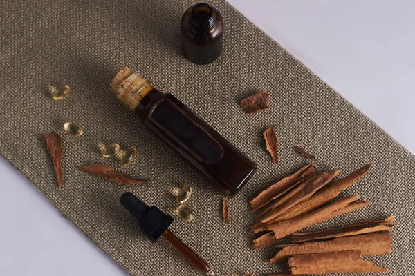 cinnamon oil in glass bottle and cinnamon in white cup and dropper with cinnamon oil