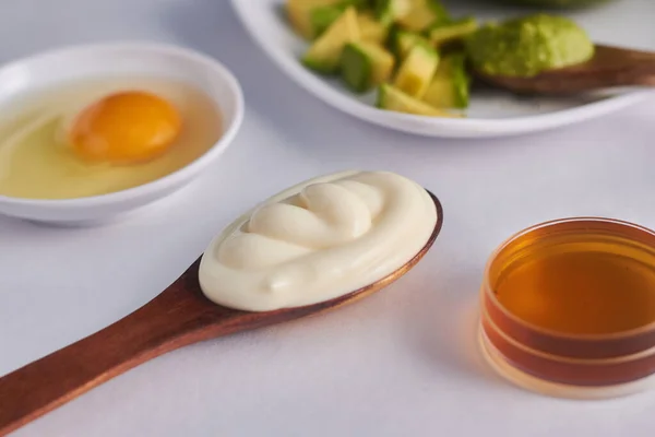 kaşık ve bal içinde mayonez avokado yumurtası maskesi