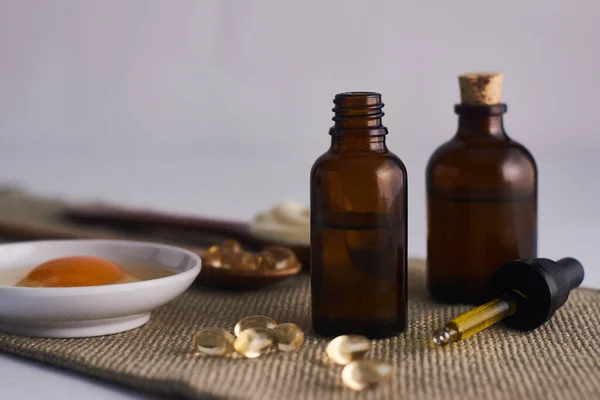 Cam kavanozda zeytinyağı maskesi ve kaşıkta mayonez ve beyaz arka planda E vitamini.