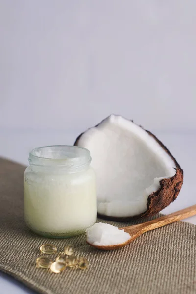 Cam şişede hindistan cevizi yağı ve tahta kaşıkla beyaz arka planda e vitamini.