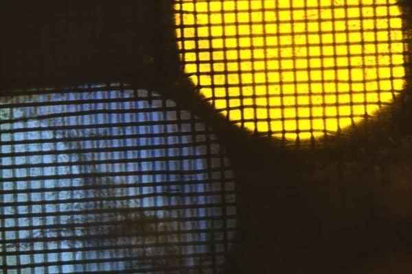 Abstracción de luces detrás de malla metálica —  Fotos de Stock