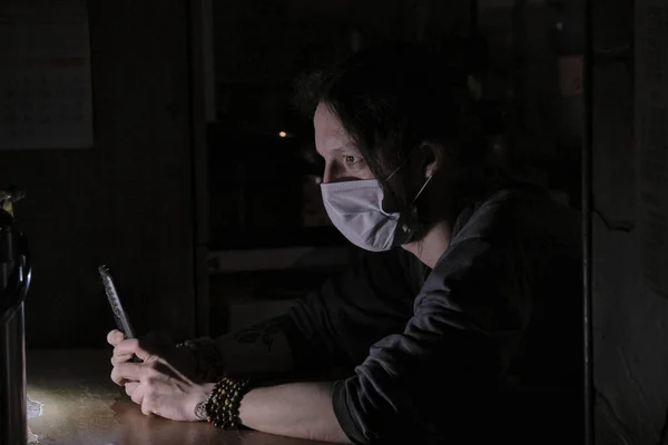 man in a medical mask at the table low light