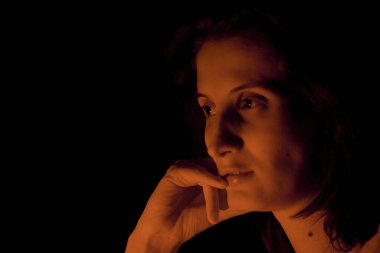 Siyah arka planda sıcak kırmızı ışık altında bir kızın portresi.