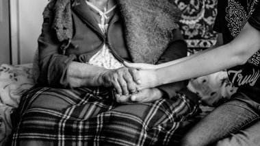 Yaşlı bir adamın elleri genç bir adamın ellerinde. Siyah ve beyaz.