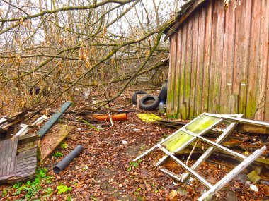 Sonbaharda terk edilmiş evde çöpler, etrafta eşyalar var.                 