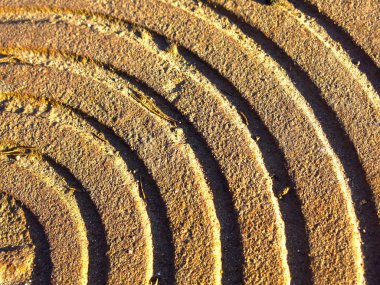 Paslı kanalizasyon kapaklarından oluşan metal spiral güneş tarafından aydınlatılıyor.