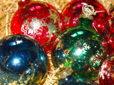 multicolored vintage glass Christmas balls with peeling paint on a straw background
