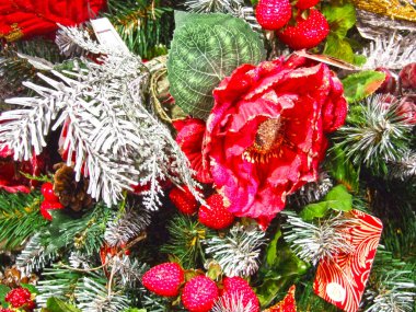 Christmas tree decoration in the house: snow-covered coniferous tips of artificial spruce branches, red rose, raspberry, cones, Holly berries