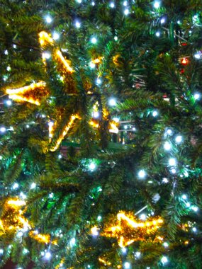 Altın madalyalı sokak Noel ağacı: parlak bir yıldız, çiçekler, toplar ve yaylar