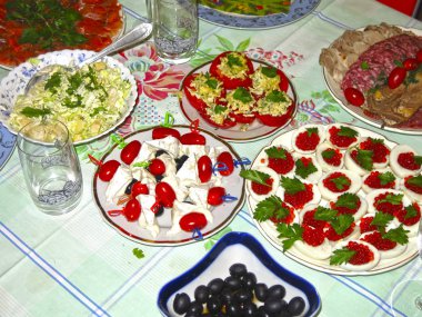 Festival masası seti: dilimlenmiş et, kanepe, peynir, zeytin, yumurta içinde havyar, peynirli domates ve sarımsak.