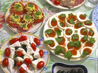 Festival masası seti: dilimlenmiş et, kanepe, peynir, zeytin, yumurta içinde havyar, peynirli domates ve sarımsak.