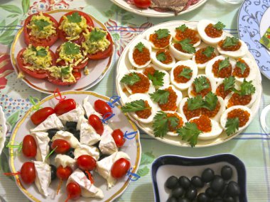 Festival masası seti: dilimlenmiş et, kanepe, peynir, zeytin, yumurta içinde havyar, peynirli domates ve sarımsak.