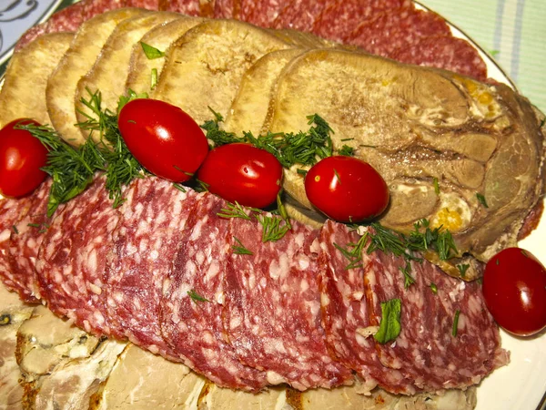 festive meat cuts: beef tongue, salami sausage, ham, pork, cherry tomatoes