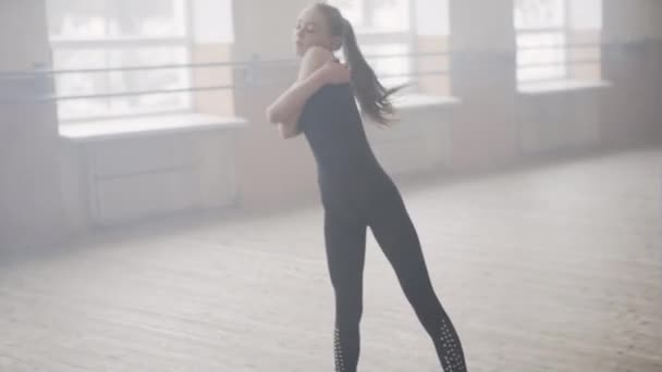 Giovane ballerina di balletto in abbigliamento sportivo nero che pratica da sola in una grande sala vuota — Video Stock