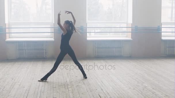 Unga kvinnliga balettdansös hoppa i studio på svart bakgrund, modern dansstil, fitnesscenter. Slow motion. — Stockvideo