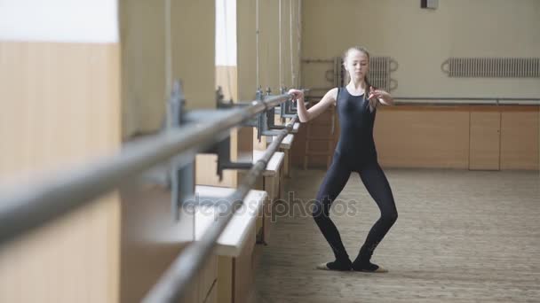 Joven bailarina de ballet elegante en ropa de entrenamiento haciendo ejercicio en clase de ballet. Primera posición . — Vídeos de Stock