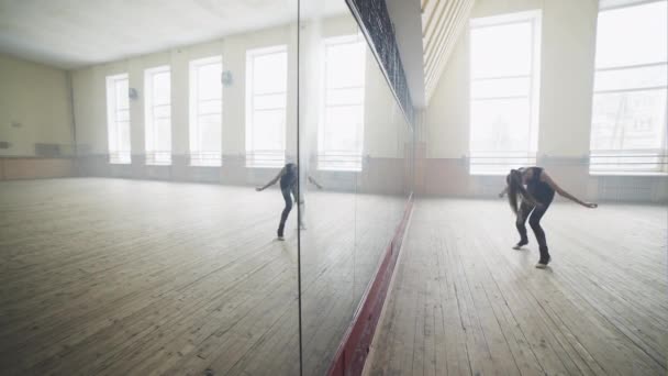 古典的な明るい部屋で鏡の前に複雑な現代アクロバティックなダンスの訓練を受けた若い女の子 — ストック動画