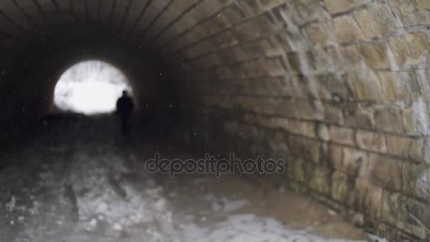De arme verwarde jongen loopt uit de lange tunnel van de oude op zoek naar iets. Winter, koud. — Stockvideo