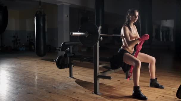 Фитнес-девушка позирует на скамейке в тренажерном зале — стоковое видео