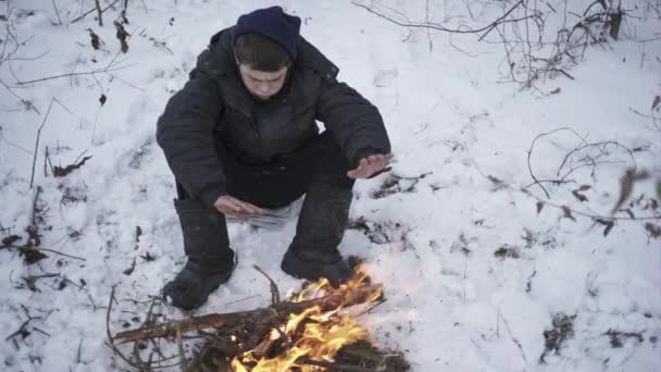 A téli időszakban a tűz mellett melegedett egy szegény fiú — Stock videók