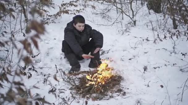 Üldögél a tábortűz szegény elveszett fiú téli erdőben — Stock videók