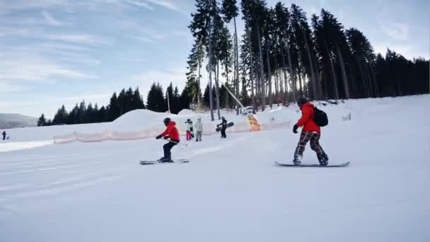 男のスノーボーダーから滑り降りて山冬の日、冬のリゾート地で雪に覆われた斜面を見下ろす — ストック動画