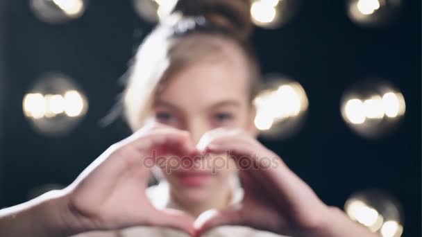 En ung jente som lager hjertesymbol med hendene og viser tommelen opp – stockvideo
