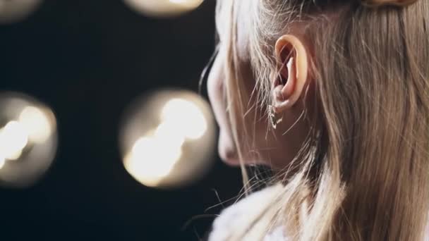 Close up retrato de uma menina adorável em um fundo preto com lâmpadas — Vídeo de Stock