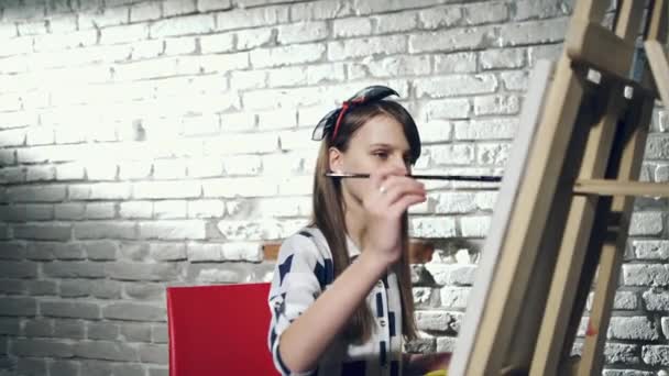 Kreativer, nachdenklicher Maler Kind malt in Werkstatt ein buntes Bild auf Leinwand mit Ölfarben. — Stockvideo