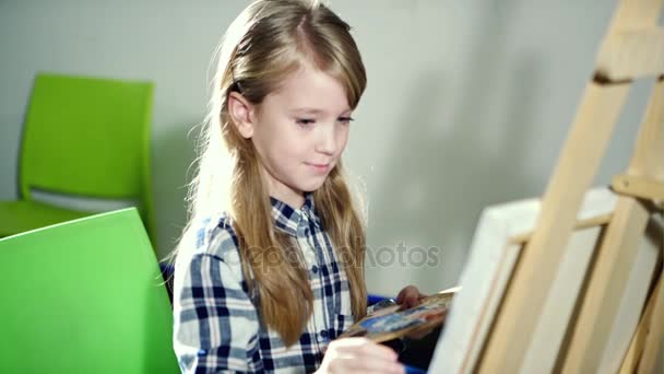 Retrato de una niña encantadora pintando un cuadro en un estudio o escuela de arte . — Vídeo de stock