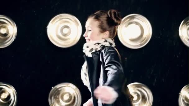 Young funny girl in leather jacket happy and smiling at the camera. Recording in the studio on a black background with light. — Stock Video