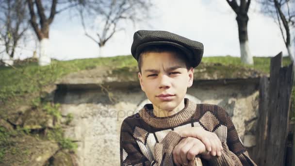 Portret van een arme tiener jongen in een hut bij de ingang van de opslag voor de winter — Stockvideo