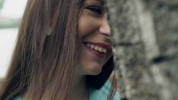 Menina agradável sorri atrás da árvore — Vídeo de Stock