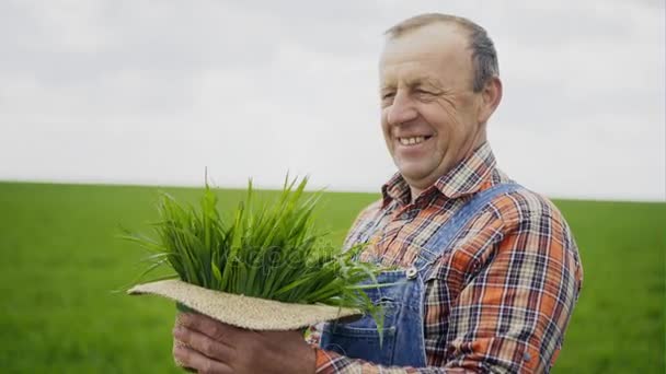 Oudere mannelijke boer met groene planten in zijn hoed — Stockvideo