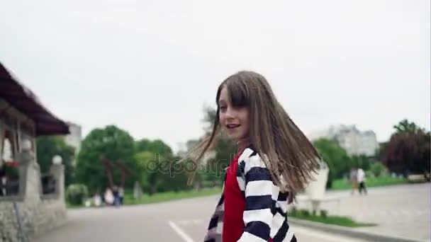 Щаслива дівчина-підліток з красивим довгим волоссям кружляє в парку — стокове відео