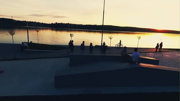 Menschen erholen sich im Sommer bei Sonnenuntergang aktiv am Wasser der Stadt - Luftaufnahme — Stockvideo