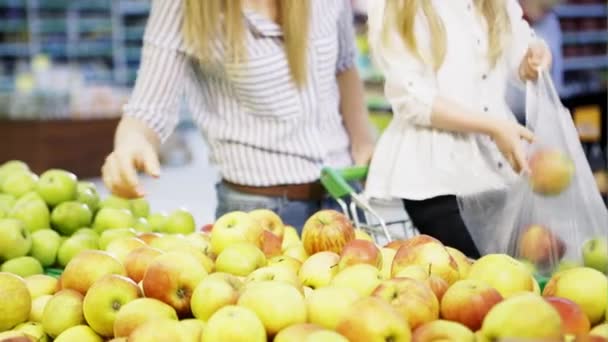 Een dochter en moeder verzamelen appels om te winkelen in een supermarkt — Stockvideo