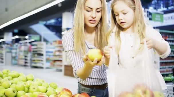 Una niña con su madre compra manzanas en un supermercado — Vídeos de Stock