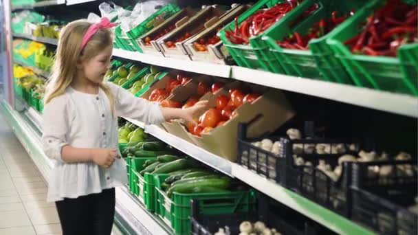 Młoda dziewczyna wybiera pomidora w supermarkecie i jest szczęśliwy, gdy stwierdzi, że — Wideo stockowe
