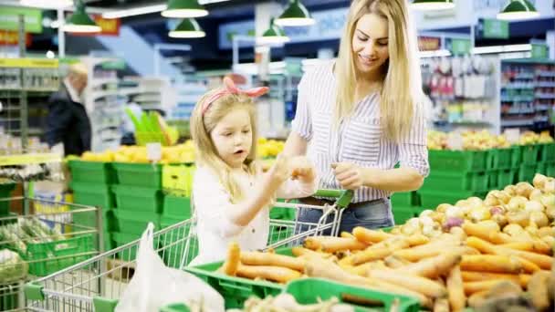 ママと彼女の小さな娘がスーパーで新鮮なニンジンを購入します。 — ストック動画