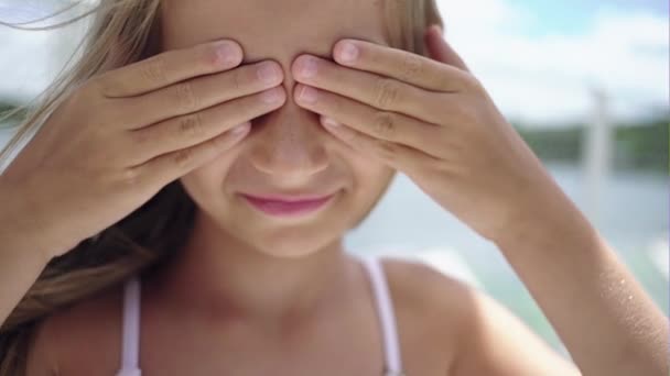 Schattig klein meisje die betrekking hebben op haar gezicht met haar handen. — Stockvideo